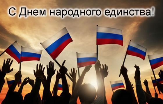 Руки людей держат флажки РФ на фоне заката с днём народного единства